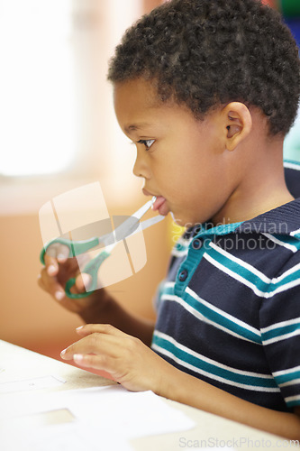 Image of Boy, scissor danger and learning in classroom for blade by tongue for development, growth or preschool scholarship. African kid, sharp object and mouth with paper, injury or education at kindergarten