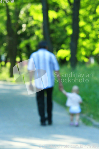 Image of happy father with her baby walk by hand in the park