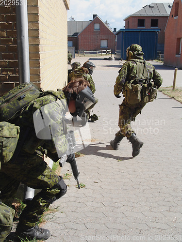 Image of Army, soldier and training by building with weapon for fitness, exercise or challenge outdoor with gear. Military, people and running for workout, mission or bootcamp with camouflage for survival