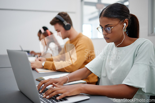 Image of Students, elearning and laptop in classroom education, learning and studying with technology indoors. Focused woman typing research essay or project on computer at university, college or school