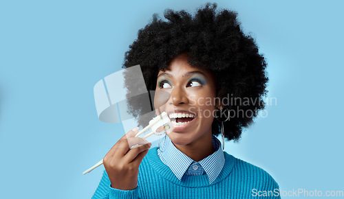 Image of Happy, food and black woman with sushi in a studio eating with japanese chopsticks with mockup space. Healthy meal, smile and african girl with a afro enjoying delicious sashimi with blue background.