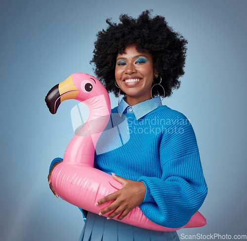 Image of Portrait of woman in blue with a flamingo and a smile on her face. Happy black woman with inflatable bird rubber ring on hip on blue background. Mockup for trendy, travel and fun for summer vacation