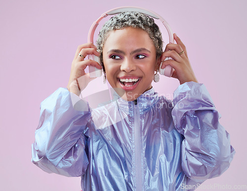 Image of Black woman and holding headphones in studio for music streaming entertainment with pink wall. Mockup pink background with happy, funky and edgy african fashion girl enjoying bluetooth audio.