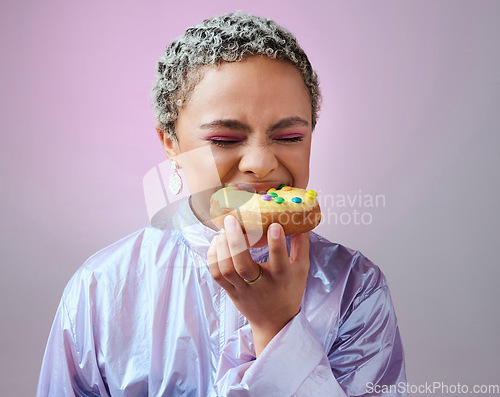 Image of Food, studio and woman is eating a donut cake with eyes closed enjoying sweet icing and sugar pastry alone. Hungry young girl on a fast food diet with a big bite on a doughnut snack as a cheat meal