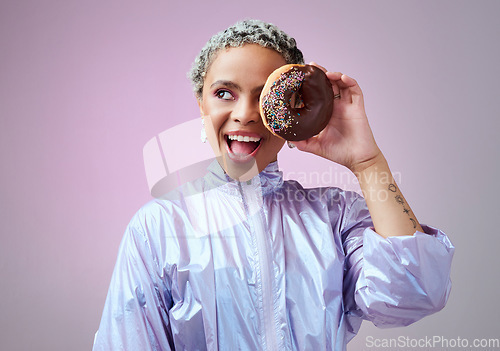 Image of Fashion, donut and black woman excited and happy about dessert with futuristic vaporwave or holographic style clothing against purple background. Face of a happy female model looking cool and trendy