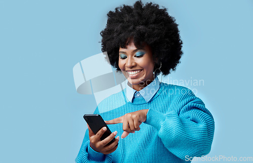 Image of Happy, phone and black woman reading a blog on an internet website in a studio with mockup space. Happiness, smile and african girl networking on social media on as smartphone with a blue background.