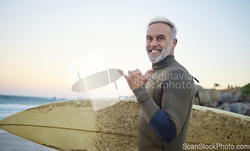Image of Summer, surfing and portrait of old man at the beach in the morning. Retired senior man with surfboard, hand sign and smile on face ready to surf at sunrise. Ocean, hobby and water sport in Australia