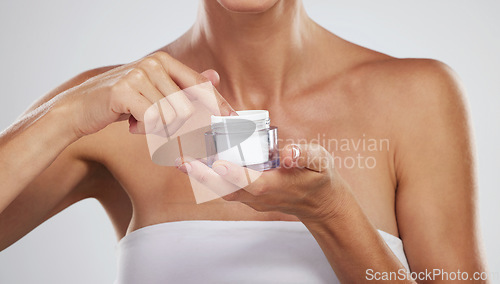 Image of Cream, beauty skincare and hands of woman with product for body wellness against a grey studio background. Spa model with natural and organic lotion in container for clean body and dermatology health