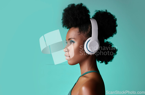 Image of Music, designer headphones and black woman thinking while listening to podcast against a blue mockup studio background. African model streaming audio from radio with creative idea nd mock up space