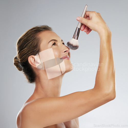 Image of Woman, makeup brush and face product in skincare routine for cosmetics beauty powder on grey studio background with mockup space. Smile, happy or playful mature model from Turkey grooming in wellness