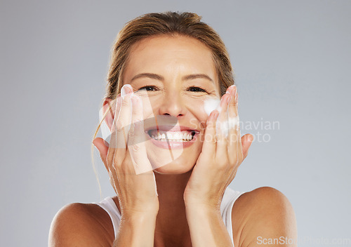 Image of Skincare, clean and face portrait of a woman washing her skin with beauty treatment in a studio. Happy, smile and healthy mature lady with health, hygiene and self care lifestyle doing facial routine