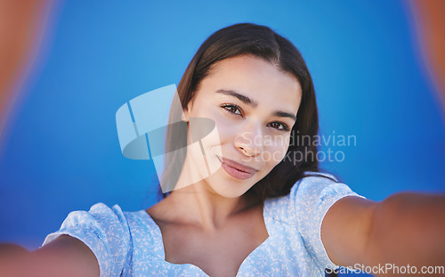 Image of Smile, happy and taking selfie with woman showing face during travel against blue background. Pov portrait of smiling female with natural beauty taking a photo and having fun for social media