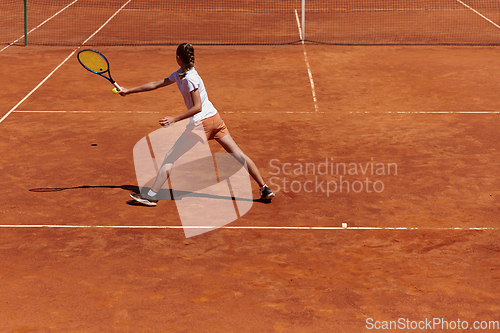 Image of A young girl showing professional tennis skills in a competitive match on a sunny day, surrounded by the modern aesthetics of a tennis court.