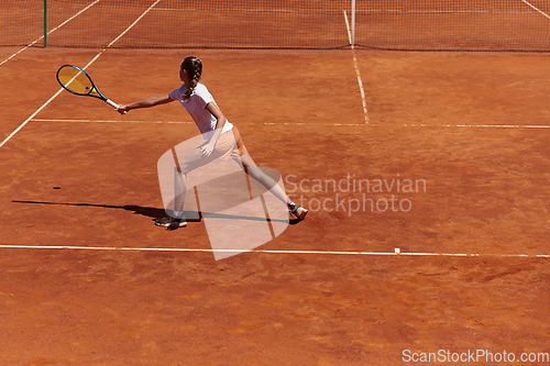 Image of A young girl showing professional tennis skills in a competitive match on a sunny day, surrounded by the modern aesthetics of a tennis court.