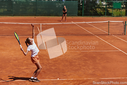 Image of Young girls in a lively tennis match on a sunny day, demonstrating their skills and enthusiasm on a modern tennis court.