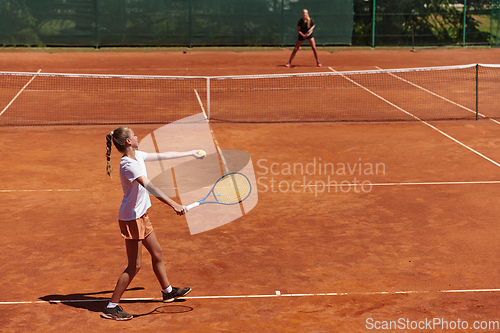 Image of Young girls in a lively tennis match on a sunny day, demonstrating their skills and enthusiasm on a modern tennis court.