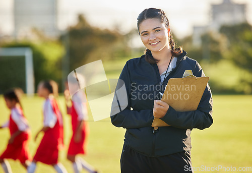 Image of Soccer field, woman coach with and girl team training on grass in background. Sports, youth development and teamwork, a happy young female volunteer coaching football team with clipboard from Brazil.