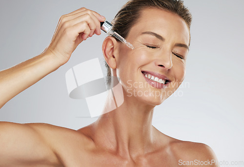 Image of Face oil, skincare and mature woman with smile for dermatology product against a grey mockup studio background. Elderly model happy with natural facial liquid collagen serum for body wellness