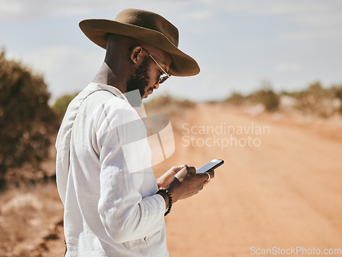 Image of Dessert dirt road, black man and phone text in nature on a vacation lost and waiting for a lift. 5g internet, mobile and web app usage of a person from Madrid wait for a taxi to travel in summer