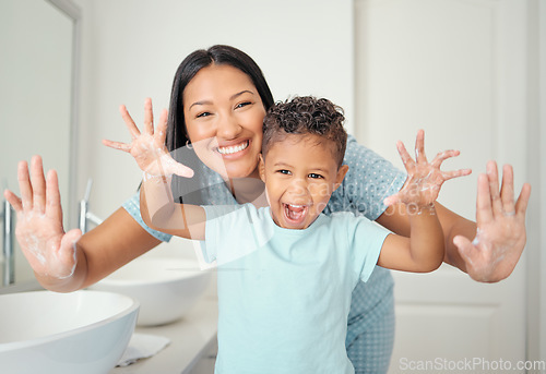 Image of Mother and son in bathroom with clean hands, open palms that are cleaned and covered in foam teaching child hand washing. Cheerful parent help kid with hygiene for hand with water, soap and bubbles.