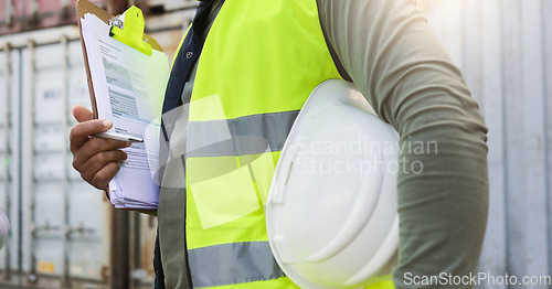 Image of Man, checklist and work in logistics with helmet by container at port. Black man, notes and pen in hand to check stock while working in shipping, cargo and transportation industry in Cape Town