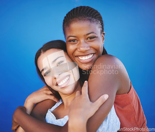 Image of Happy, friends and portrait of women hugging for support, empowerment and love in studio. Happiness, smile and interracial girls with friendship embracing with care while standing by blue background.