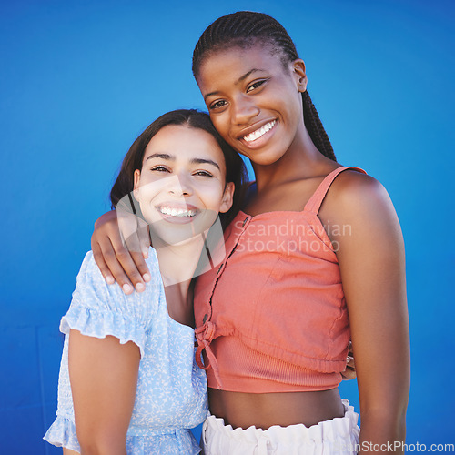 Image of Black women, friends and hug with happy smile on a blue studio background. Portrait, diversity and lesbian couple in love embrace, care and support posing, bonding and spending quality time together.