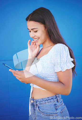 Image of Phone, social media and communication with a woman on a blue background for networking or connectivity. App, smile and 5g mobile technology with a female dating online or sending a text message