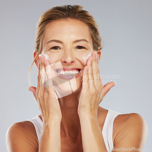 Image of Mature beauty portrait, face wash and happy woman glowing skincare, dermatology and anti aging cosmetics on grey studio background. Happy Canada lady facial cleaning soap foam, wellness and selfcare