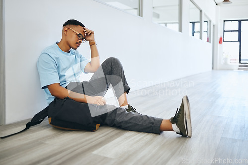 Image of Depression, mental health and student thinking on a floor, stress and social anxiety at university. Fear, debt and bully risk by black man hiding in an empty lobby, looking hopeless and overwhelmed