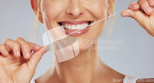 Image of Teeth flossing, dental wellness and woman with smile while cleaning mouth against grey mockup studio background. Hands of model with string to care for tooth health and oral healthcare with smile