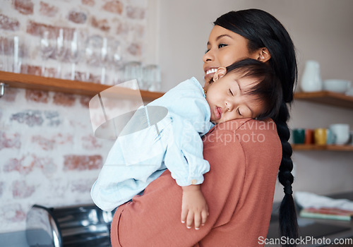 Image of Care, love and mother holding sleeping baby with down syndrome in the kitchen of their house. Newborn child with development problem sleep with happy mom with smile and comfort in their family home