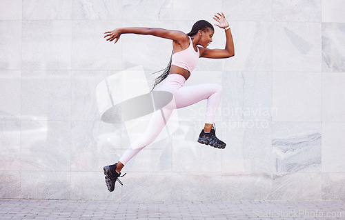 Image of Energy, sports and black woman jump running outdoor for fitness, wellness and outdoor training with wall mockup. Young, healthy african girl in athlete runner clothes for fashion mock up background