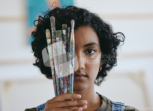 Image of Brush, portrait and woman is a creative painter in an art gallery or workshop studio for watercolor painting. Freedom, artist and Indian girl with paintbrushes for her craft, hobby and drawing talent