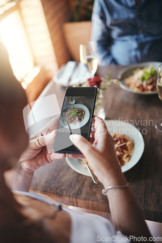 Image of Phone, food and social media with the hands of a woman taking a photograph while eating in a restaurant during a date. Mobile, internet and romance with a female snapping a picture while dating