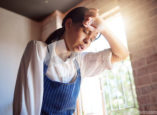 Image of Woman, tired and apron tired from working in cafe, home or cooking job. Girl, chef and cook with headache from cooking burnout or work for service in cafe, kitchen or coffee shop in London