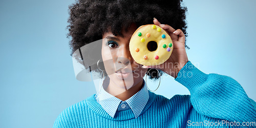 Image of Beauty, black woman and donut portrait over face, celebration of Africa and sweet style on eye with blue background. Fashion, African model and cake with feminism, empowerment and excited happiness.