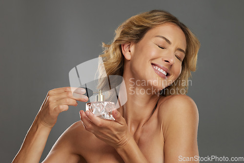 Image of Mature woman, spraying beauty perfume scent and smiling in gray studio background mockup. Bottle of fragrance spray for happy women, self care wellness and luxury cosmetic product for body wellbeing