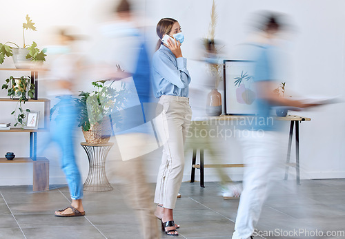 Image of Covid, office and woman on phone call standing with face mask around work colleagues in motion blur. Female employee on mobile smartphone calling in a busy workplace of fast business people walking