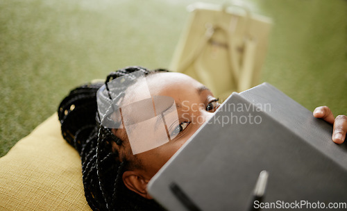 Image of Black woman and student hiding face with notebook on casual college study lounge bean bag. Shy African university learner on studying rest break looking with lecture book to hide identity.