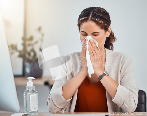 Image of Covid, sick and woman blowing her nose with a tissue while working in her modern office during pandemic. Flu, cold or sinus allergy sneeze of girl from mexico sitting at her desk with health problems