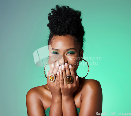 Image of Beauty, green fashion and makeup with a black woman laughing in studio on a wall background. Portrait, happy and funny with an attractive female joking inside while her hands are on her face