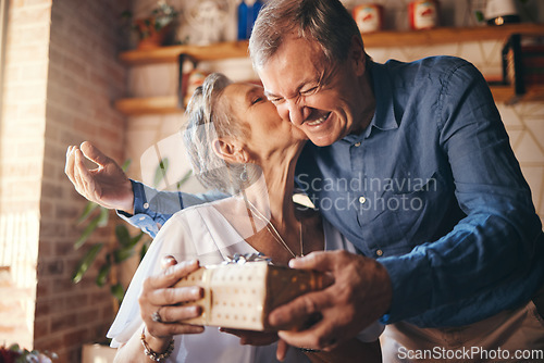 Image of Elderly, couple and happy with gift, surprise and kiss on face together in home. Man, woman and retirement show love, romance and happiness giving present for anniversary, birthday or mothers day