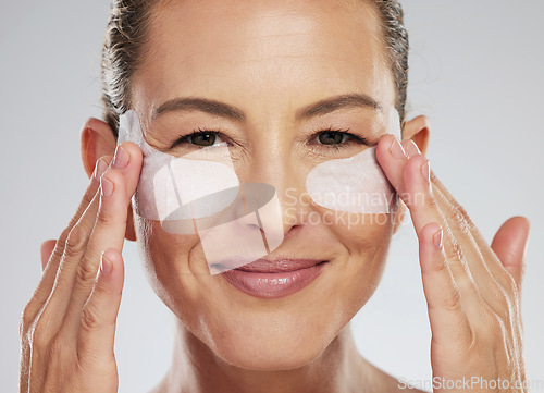 Image of Eye wellness, skincare and mature woman with dermatology product for face against a grey studio background. Portrait of an elderly spa model with patch cosmetics for eyes for clean facial skin