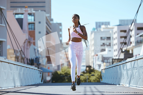 Image of Exercise workout of black woman running for health and fitness across city bridge. Training for better cardio, endurance and motivation for an active lifestyle in this urban scene.