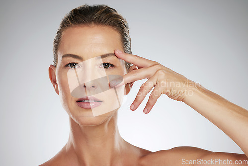 Image of Face, beauty and eyes with a mature woman taking care of her eye or skin in studio on a gray background. Skincare, cosmetics and antiaging with an attractive female posing for wellness and vitality