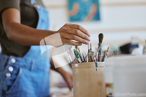 Image of Woman, artist and hand of painter reaching for paintbrush in studio, creative workshop or art class painting. Closeup of female doing artwork and craft as hobby with a brush set or collection inside