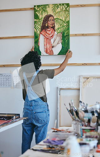 Image of Painter, artist and wall hanging painting in studio to dry before exhibition, sale or display. Art, creative and woman with portrait of girl in paint in workshop with canvas, brush and color in Paris