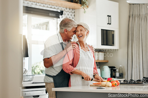 Image of Senior couple in kitchen, cooking healthy food together and happy in retirement lifestyle. Elderly woman chopping vegetables with apron, old white man hug wife in home and love nutrition dinner meal