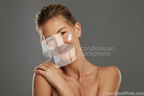 Image of Skincare, beauty and woman with face product for a morning facial healthcare and wellness routine in studio. Smile, relax and mature model happy to show her selfcare dermatology cosmetics and cream